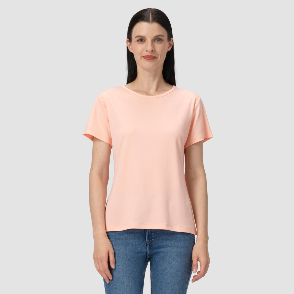 Woman wearing a light pink t-shirt and blue jeans on a gray background