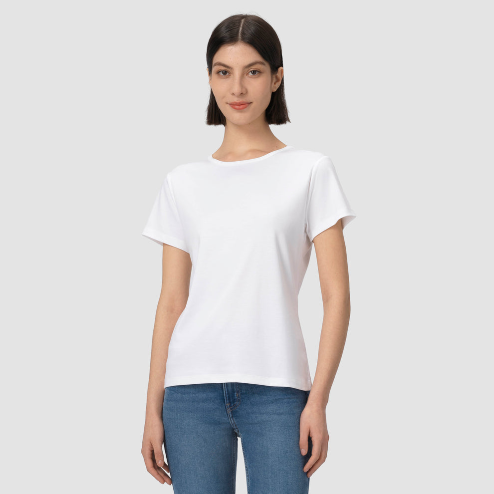 Une personne vêtue d'un t-shirt blanc uni et d'un jean bleu sur un fond gris clair