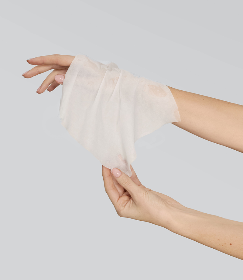 Personne tenant une lingette en coton blanc humide sur fond gris clair
