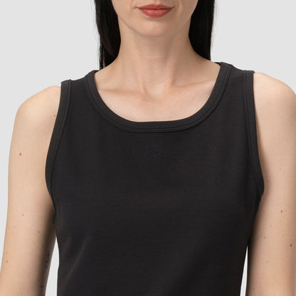 Woman wearing a black tank top against a plain background