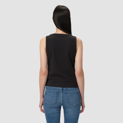 Person wearing a black tank top and blue jeans on a light gray background