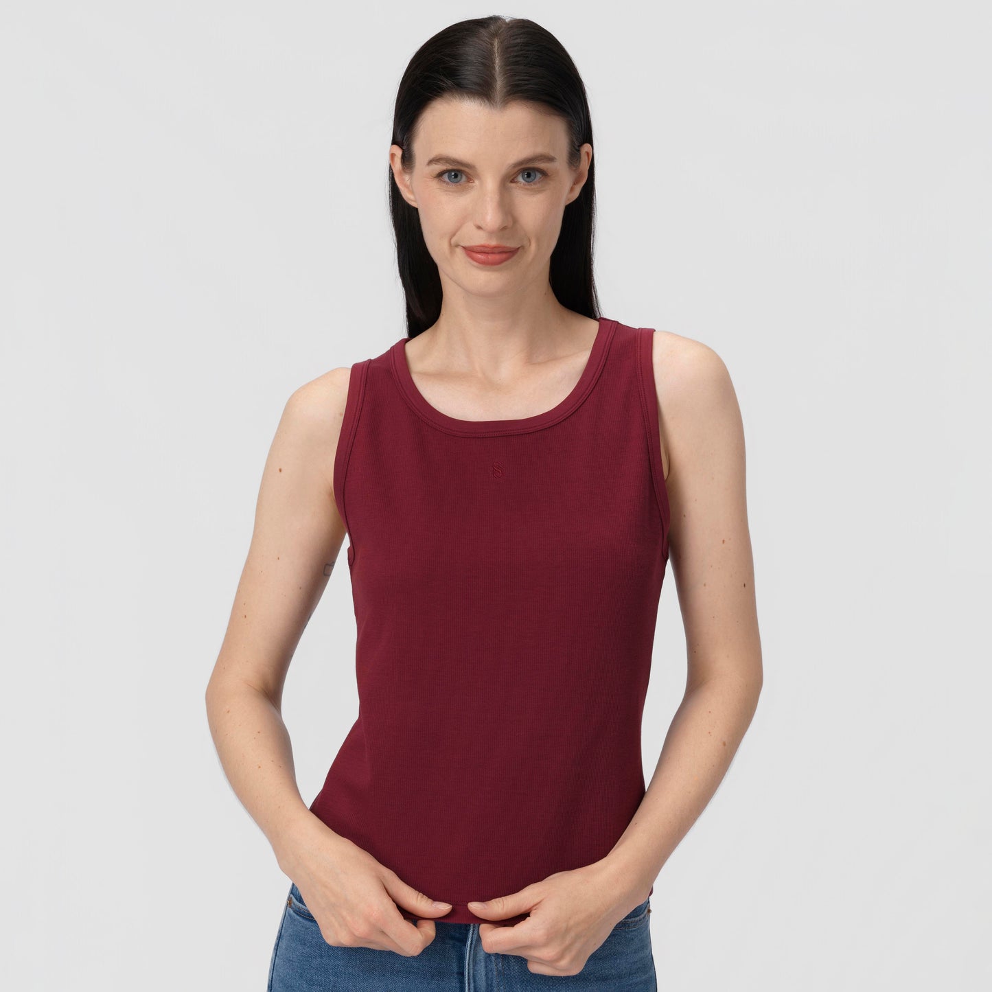 Woman wearing a burgundy tank top against a plain background