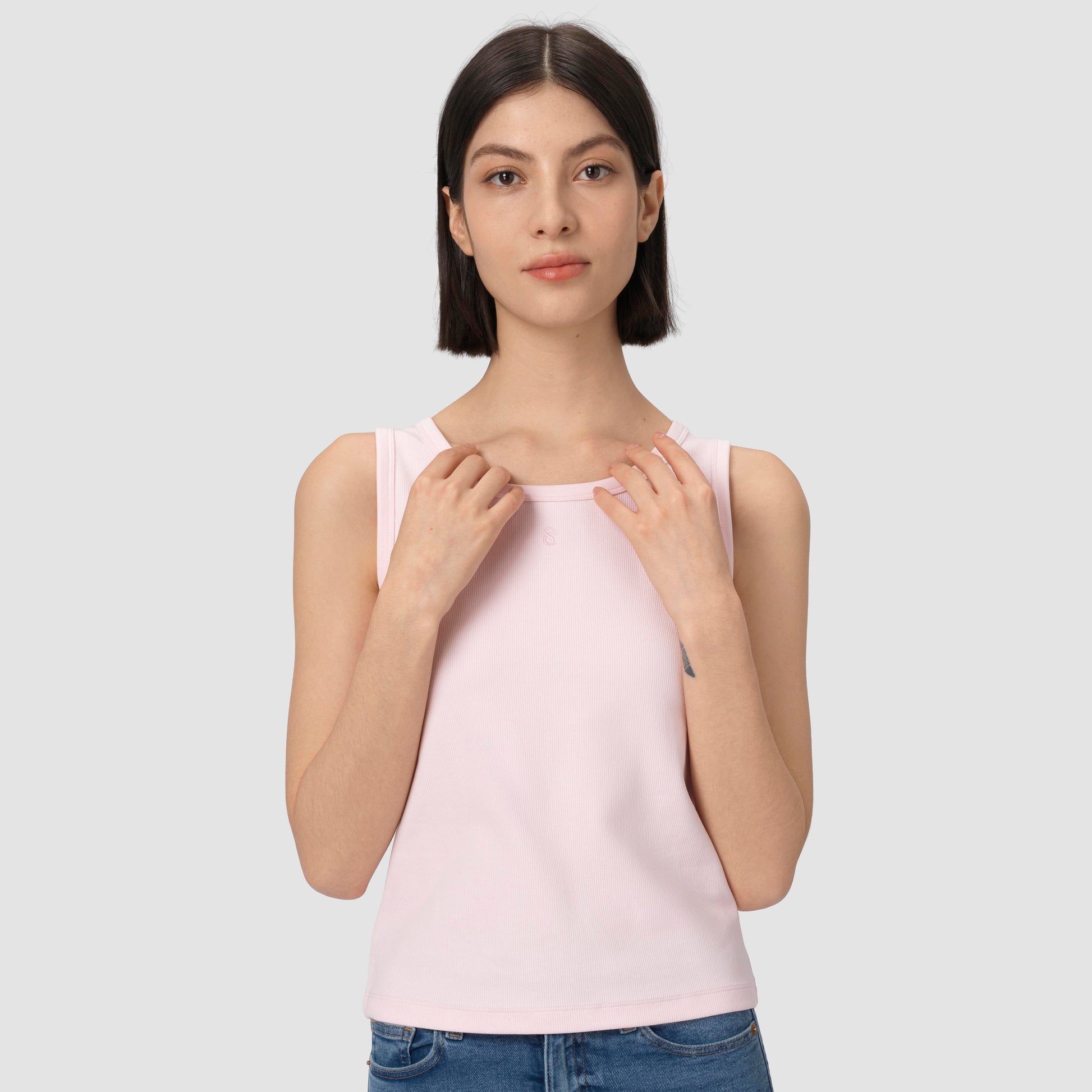 Woman wearing a light pink tank top against a plain background