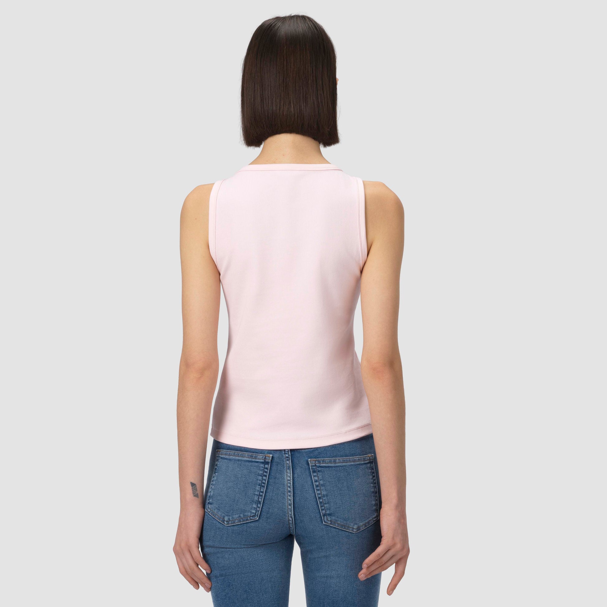 Back of a model wearing light pink tank on a grey background