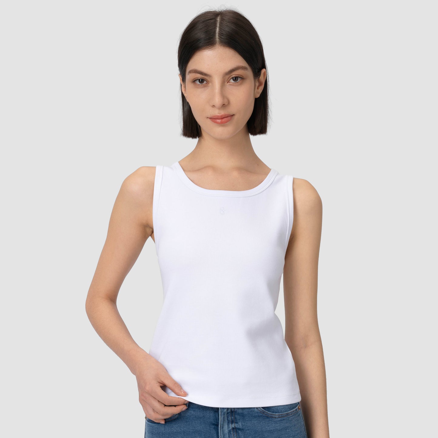 Woman wearing white tank top close up with plain background