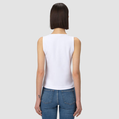 Person wearing a white tank top and blue jeans on a plain background