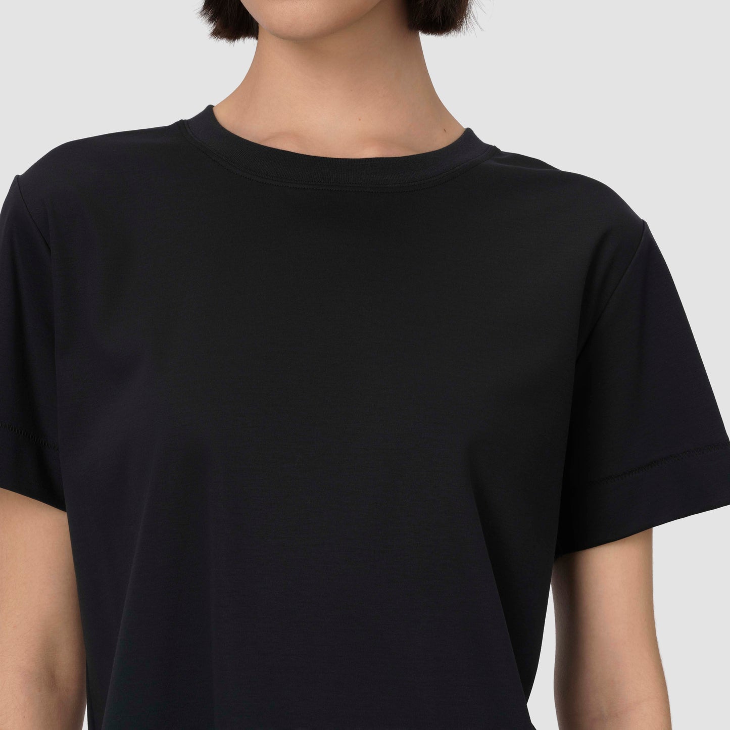 Person wearing a plain black t-shirt against a light gray background