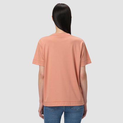 Person wearing a peach-colored t-shirt and blue jeans on a light gray background