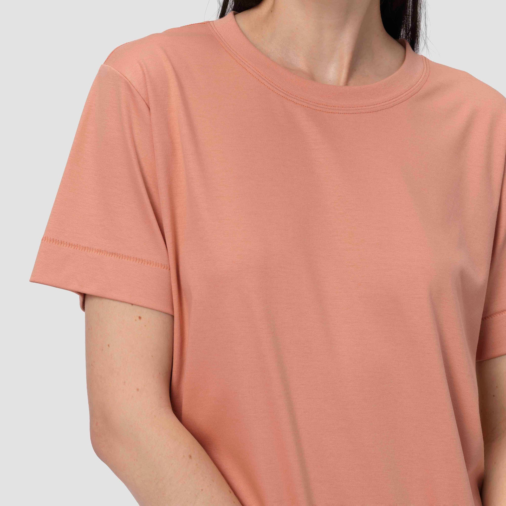 Person wearing a plain pink t-shirt against a light gray background