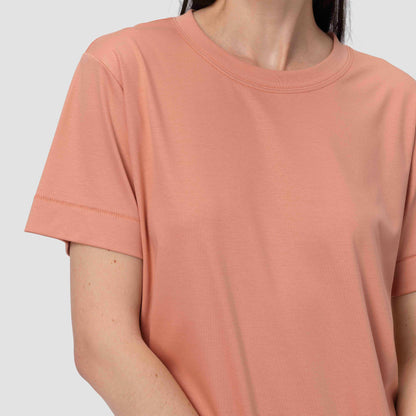 Person wearing a plain pink t-shirt against a light gray background