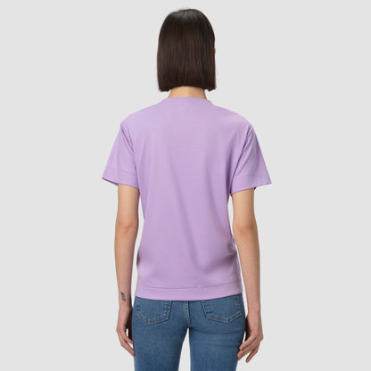 Person wearing a light purple t-shirt and blue jeans on a plain background