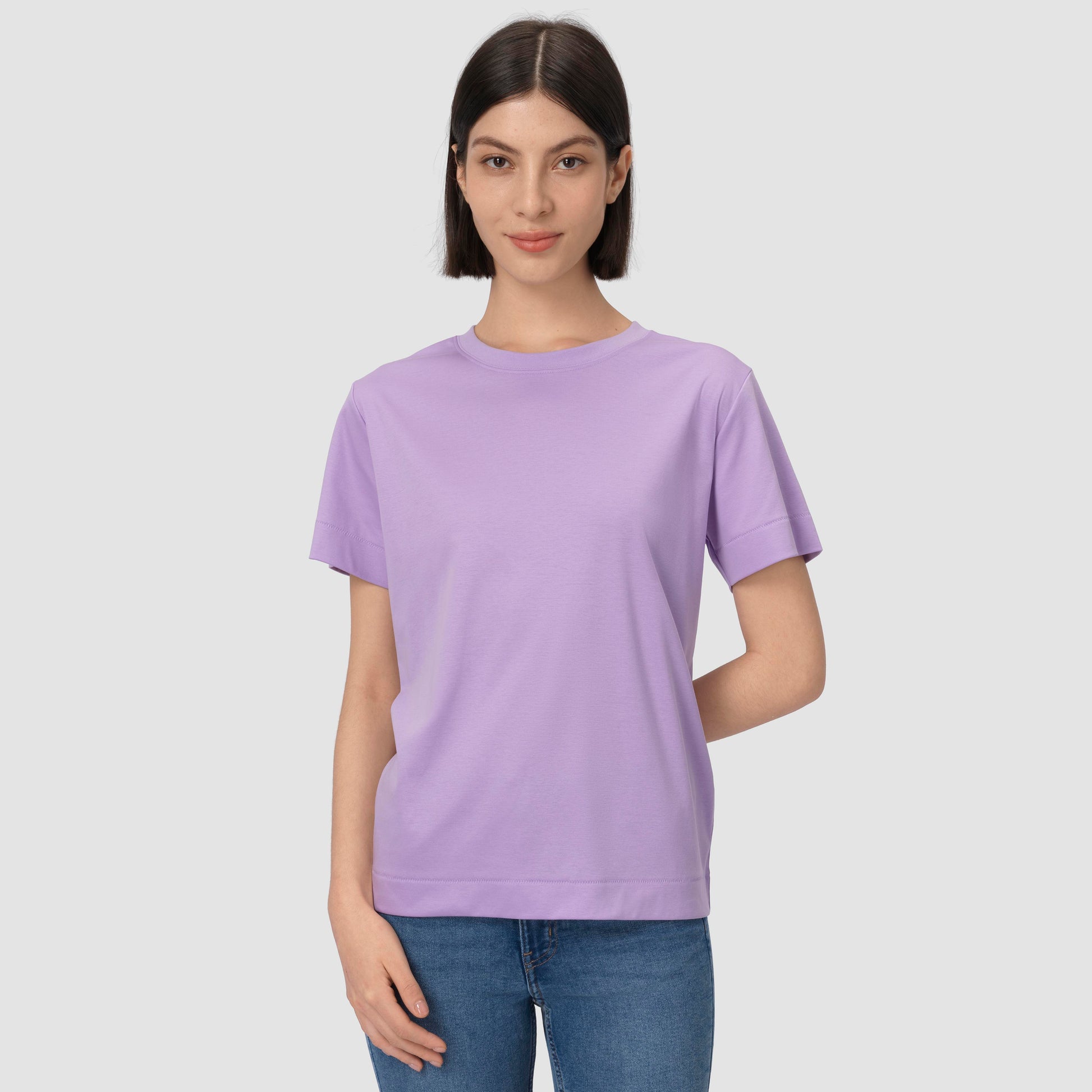 Person wearing a light purple t-shirt and blue jeans on a plain background