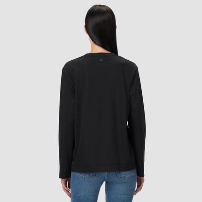 Une personne vêtue d'un t-shirt noir à manches longues et d'un jean bleu sur un fond gris clair