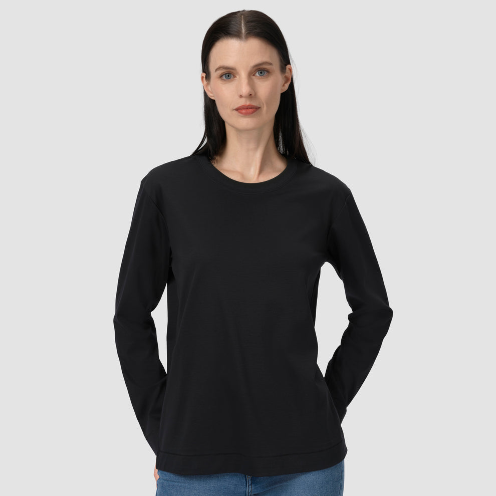 Une femme vêtue d'un t-shirt noir à manches longues devant un fond uni