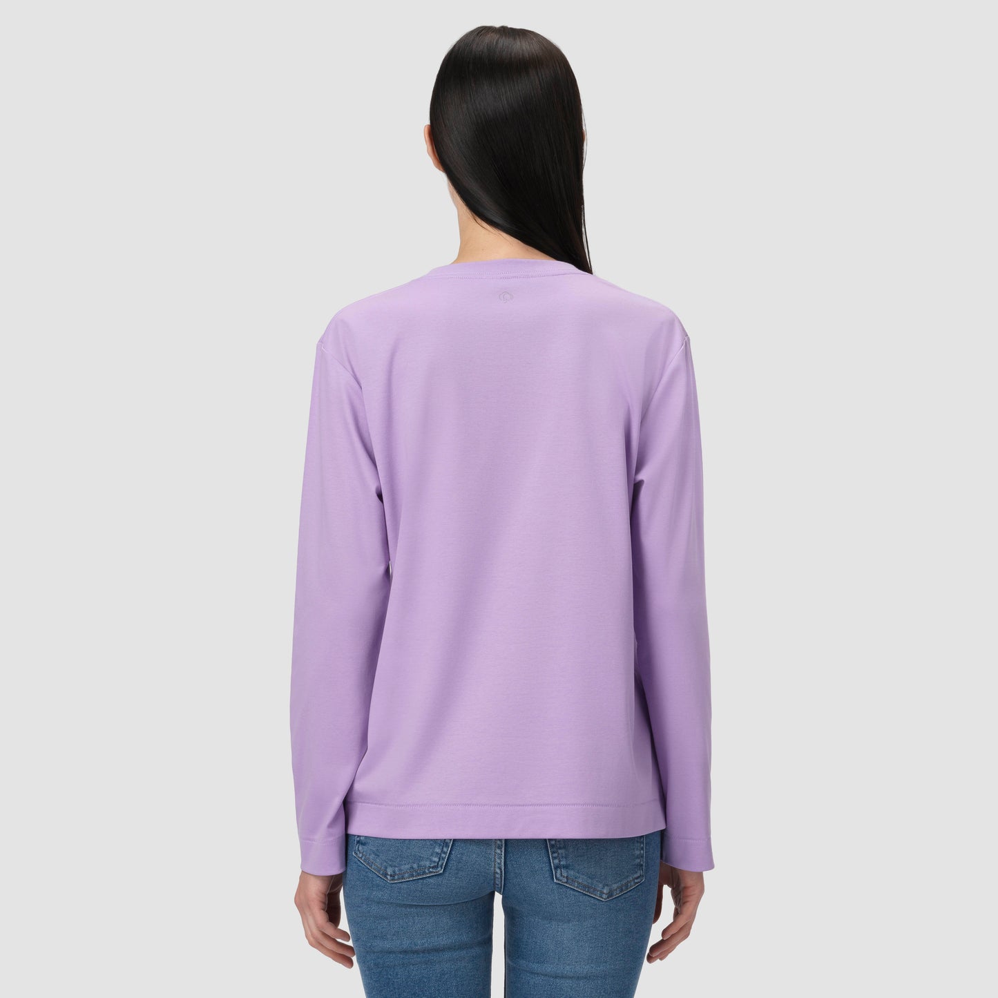 Une personne vêtue d'un t-shirt à manches longues violet sur fond gris clair