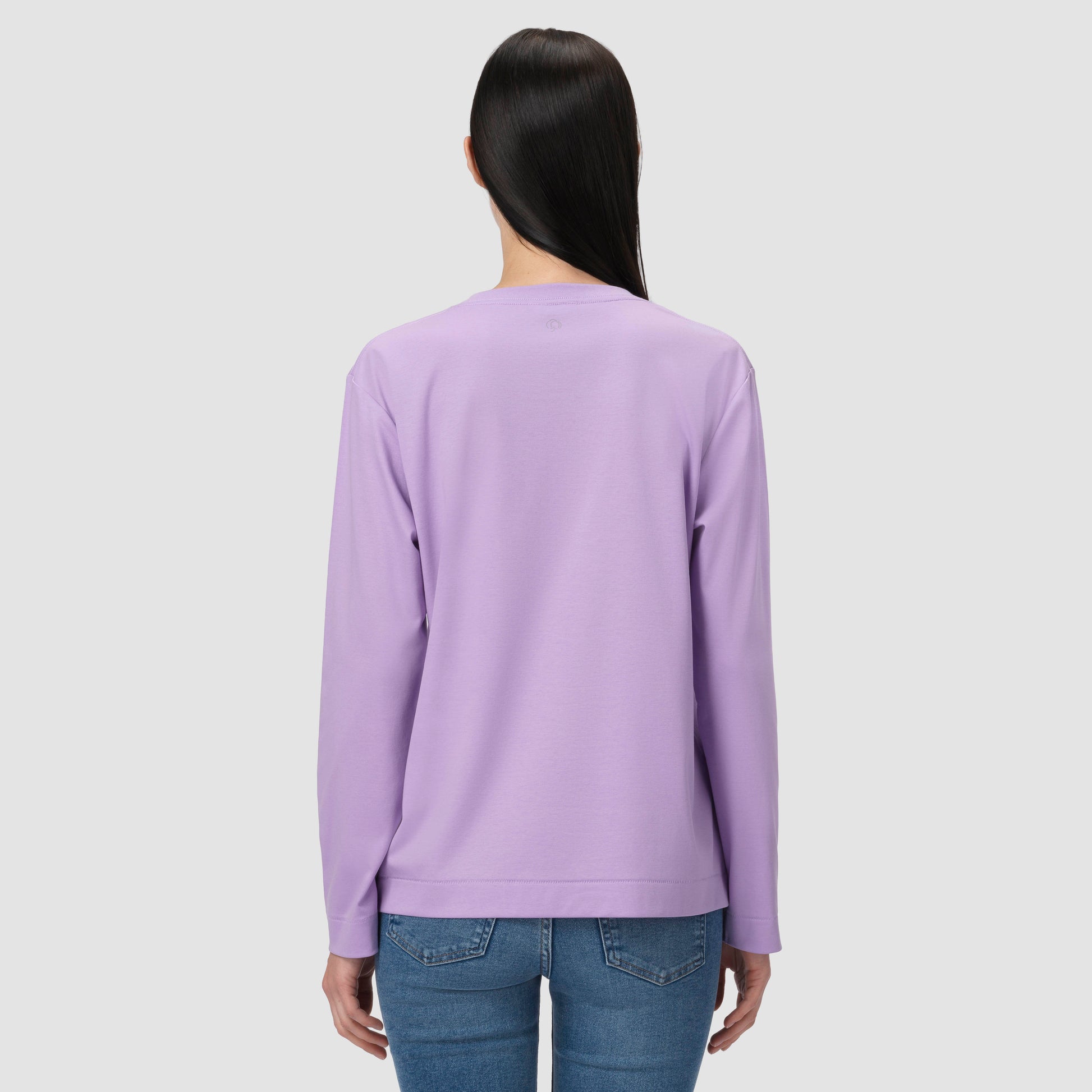 Une personne vêtue d'un t-shirt à manches longues violet sur fond gris clair