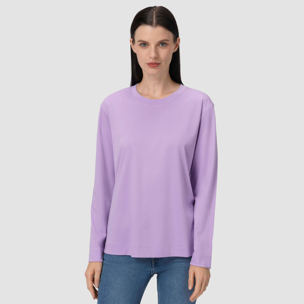 Une femme vêtue d'un t-shirt à manches longues violet clair devant un fond uni