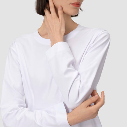 Une personne vêtue d'une chemise blanche à manches longues devant un fond uni