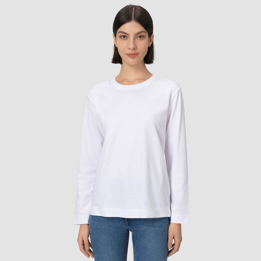 Une personne vêtue d'un t-shirt blanc uni à manches longues et d'un jean bleu sur un fond gris clair